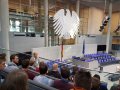 Personen sitzen auf Besuchertribüne im Plenarsaal des Bundestags