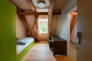 Zimmer mit Dachschräge, Gebälk, Bett und Kommode