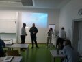 Personen stehen in einem Klassenzimmer