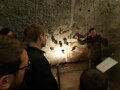 Personengruppe vor einer Wand, die zum Teil beleuchtet ist
