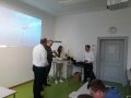 Vier Personen stehen neben Leinwand in Klassenzimmer