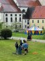 Personen stehen an Maibaum auf einer Grünfläche
