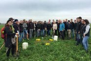 Personen stehen auf einem Feld in einem Halbkreis