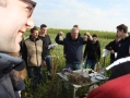 Mehrere Personen stehen im Feld um Tisch, auf dem kleine Erdhäufen sind