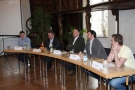 Fünf Personen sitzen nebeneinander an langem Tisch
