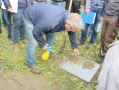Mann beugt sich über Platte, auf der Erde ist