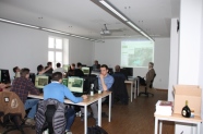 Personen sitzen an PCs in Schulungsraum